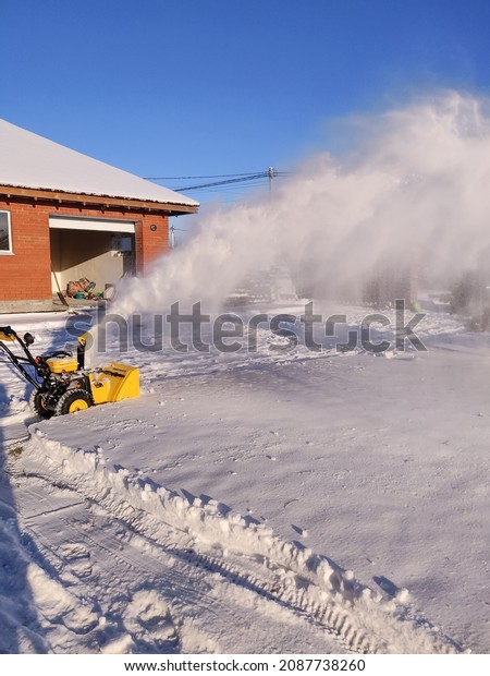 Cleaning the yard with snow blower in winter,\
seasonal activity.