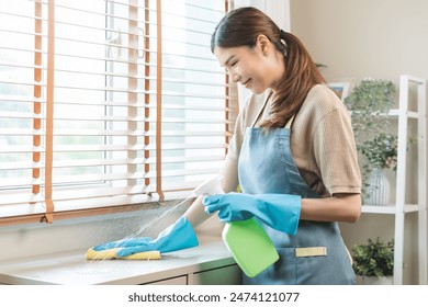 Cleanliness, asian young woman work chore cleaning on cupboard at home, hand wearing glove using wiping cloth remove dust with spray bottle. Household hygiene clean up, equipment tool for cleaning - Powered by Shutterstock