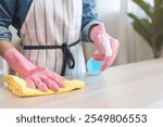 Cleanliness asian young woman working chore cleaning on table at home, hand wearing glove using rag rub remove dust with spray bottle. Household hygiene clean up, cleaner, equipment tool for cleaning