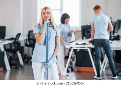 Cleans Floor. Group Of Workers Clean Modern Office Together At Daytime.