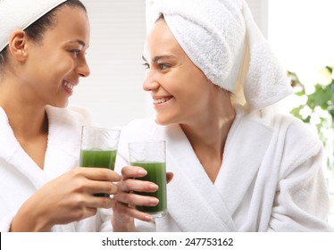 Cleansing the body of toxins, natural spa and friends for screening. Two women in wellness salon dressed in white robes vitamin cocktail drink green 