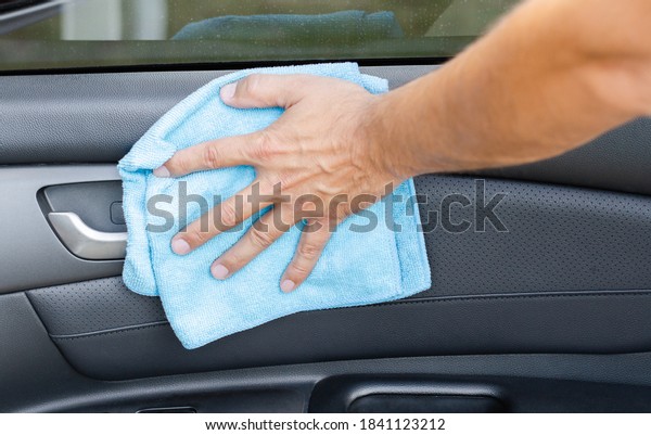 Cleansing car interior and\
door. Male hand  disinfecting vihicle inside for protection from\
virus disease
