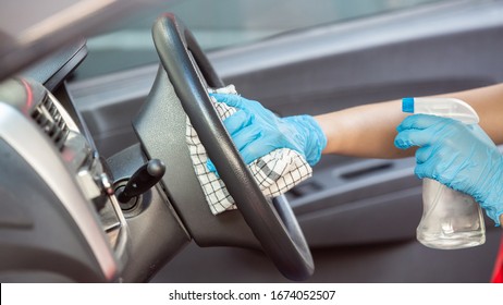 Cleansing car interior and spraying with disinfection liquid. Hands in rubber protective glove disinfecting vihicle inside for protection from virus disease