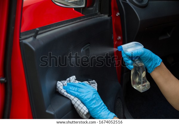 Cleansing car interior and spraying with\
disinfection liquid. Hands in rubber protective glove disinfecting\
vihicle inside for protection from virus\
disease