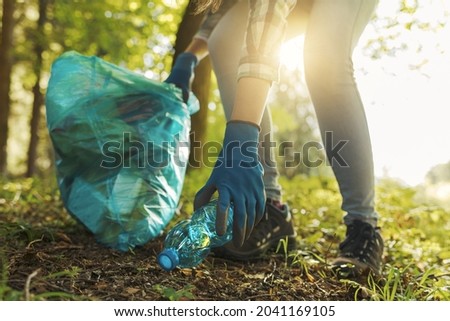 Cleanup volunteer collecting trash in the forest and holding a garbage bag, environmental protection concept