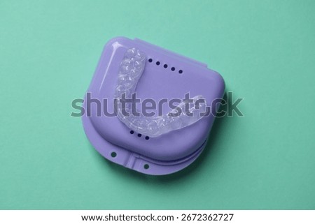 Clear aligner and retainer case on turquoise background, top view