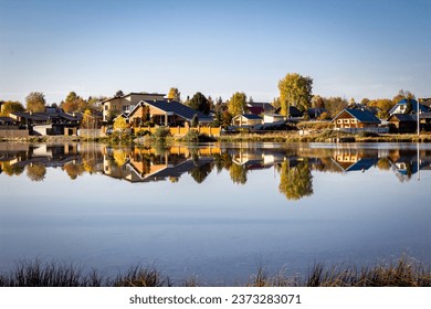 Clear autumn sunny day. There are wooden houses on the shore of the lake. Yellow leaves on the trees - Powered by Shutterstock