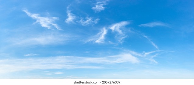 Clear azure sky with few wispy cirrus clouds. Sparse translucent white clouds in the blue sky on a sunny day. Concepts of weather forecast, vacations, travel and season. Sky only wide panorama. 
