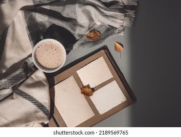 Clear blank photo frames on old album, cup of coffee with grey plaid and fall leaves. Sunday loneliness relaxing, hugge mood. Family traditions, memories and nostalgia concept. Flat lay. Autumn vibes. - Shutterstock ID 2189569765