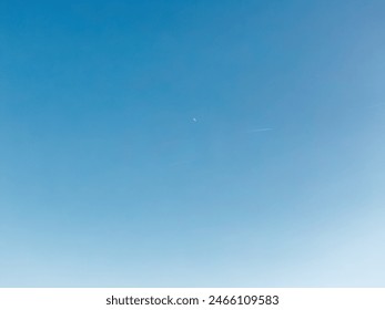 Clear Blue Sky with Airplane Contrails and Crescent Moon - Powered by Shutterstock