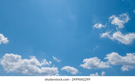 The clear blue sky, dotted with numerous small fluffy white clouds, creates a calm and open atmosphere. There is space for text. - Powered by Shutterstock