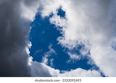 Clear blue sky with dramatic dark clouds, creating a captivating contrast. Stunning weather phenomenon showcasing the beauty of nature. Moody sky with a mix of light and shadows. Atmospheric scene