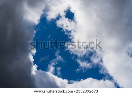 Clear blue sky with dramatic dark clouds, creating a captivating contrast. Stunning weather phenomenon showcasing the beauty of nature. Moody sky with a mix of light and shadows. Atmospheric scene