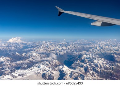 clear blue sky and the earth below cover with snow mountain, a panorama of the Alpine mountains, a view from an airplane