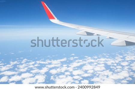 Clear blue sky with fluffy cumulus clouds, panoramic view from an airplane, wing close-up. Dreamlike cloudscape. Travel, tourism, vacations, freedom, peace, hope, heaven concepts.