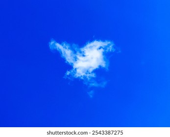 In a clear blue sky, a fluffy white cloud takes the shape of a bird, creating a whimsical view against the bright, sunny backdrop. - Powered by Shutterstock