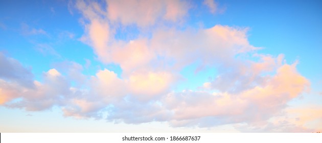 Clear blue sky with glowing pink cumulus clouds after a blizzard at sunset. Dramatic winter cloudscape. Concept art, meteorology, heaven, hope, peace, graphic resources, picturesque panoramic scenery
