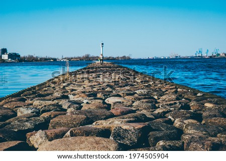 clear blue sky on the pier large stones in the foreground . High quality photo