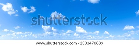 Clear blue sky panoramic background with small white clouds.