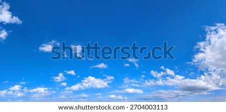 Clear blue sky panoramic background with small white clouds. The varying altitudes of the solitary clouds create a complex picture of the ease of flight and soaring above the earth. 