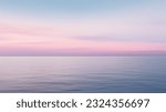 Clear blue sky sunset with glowing pink and purple horizon on calm ocean seascape background. Picturesque