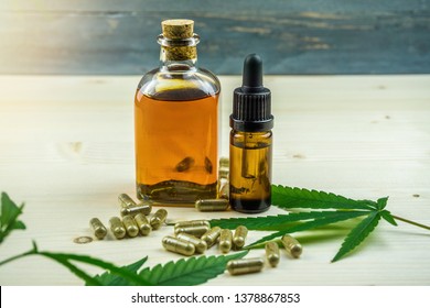 Clear CBD Cannabidiol capsules and cannabis oil on wooden backdrop
