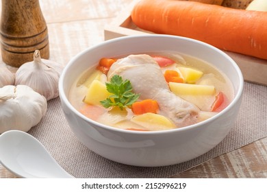 Sopa clara de pollo con papas, zanahoria y cebolla en cuenco blanco. Comida de estilo asiático