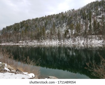 Clear Cold And Calm Winter Afternoon. Water Reflection Of The Snowy Trees Above.