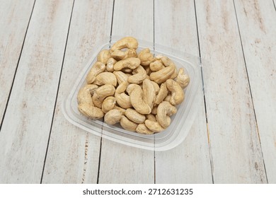 A clear container with compartments filled with assorted nuts: macadamia nuts, pecans, peanuts, and almonds, organized by section
