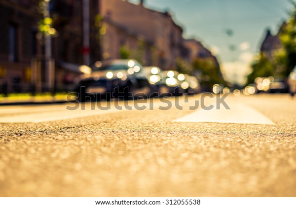 Clear day in the big city, city street with cars\
between old houses. View from the pedestrian crossing, image in the\
yellow-blue toning