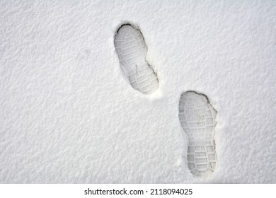 Clear deep footprints on white winter snow of a pair of boots. Track in snow. Overhead view. Texture of snow surface.foot prints in fresh snow