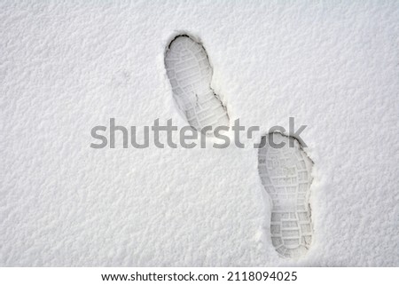 Clear deep footprints on white winter snow of a pair of boots. Track in snow. Overhead view. Texture of snow surface.foot prints in fresh snow