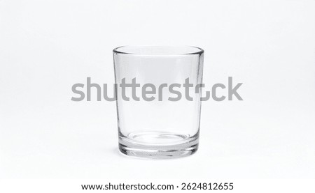 A clear, empty, cylindrical drinking glass stands on a white background. Simple design, tall and transparent, ideal for water or other beverages. Clean and modern.