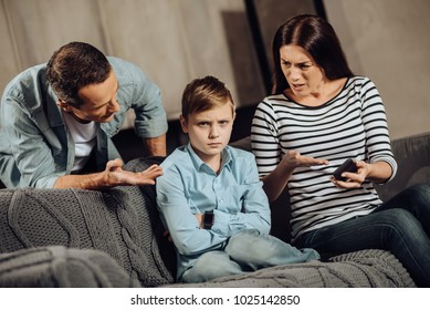 Clear Explanation. Strict Young Parents Telling Their Son About The Drawbacks Of Binge-playing On The Phone While The Boy, Scolding Him, While The Boy Looking Offended