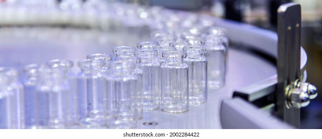 Clear glass bottles, vaccine vial transfer on automated conveyor systems automation for pharmaceutical industry.