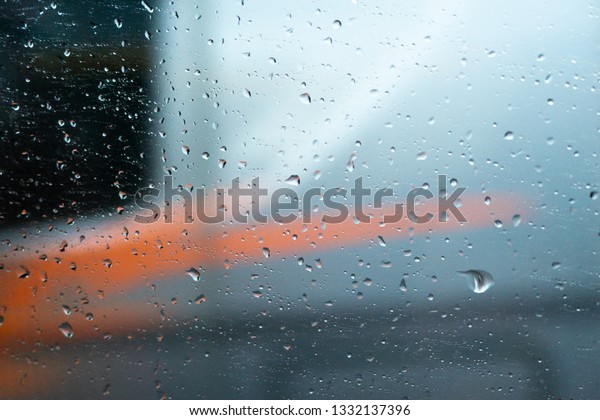 Clear glass car\
with water drops on a blue and orange background. beautiful texture\
of rain on the glass