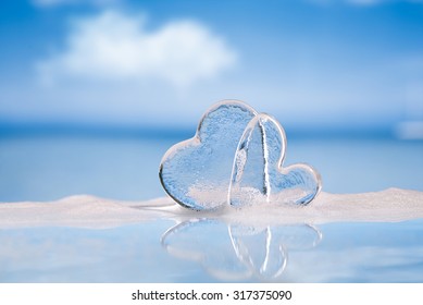 clear glass hearts in foam on wet white glass with reflection