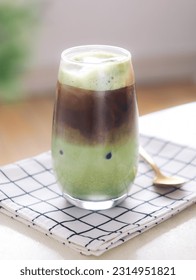 A clear glass of mixed iced matcha green tea and espresso latte. It's a trendy beautifully layered drink of matcha espresso with milk - Shutterstock ID 2314951821