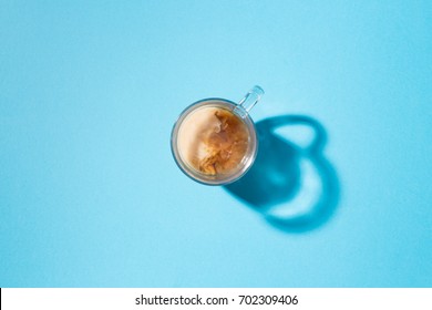 Clear Glass Mug With Coffee And Creamer In Top Down View On A Blue Background