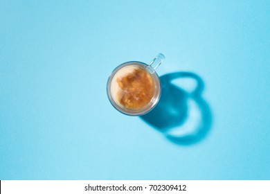 Clear Glass Mug With Coffee And Creamer In Top Down View On A Blue Background