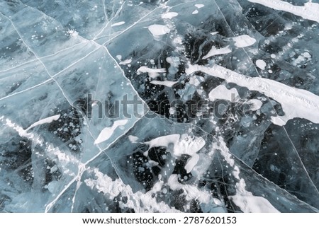Clear ice layer displays unique patterns and air bubbles, revealing natural textures in a frozen lake setting during winter season