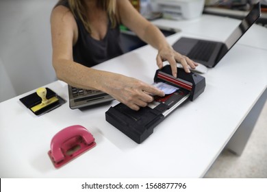 Clear image of female hand inserting  imprinting paper with credit card underneath into old pre-digital credit card imprinter machine white office table background  - Shutterstock ID 1568877796