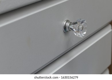 A Clear Knob On A White Dresser Drawer.