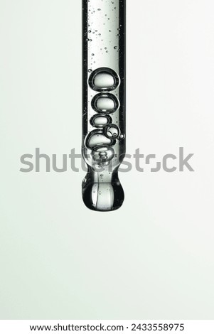 Clear liquid droplets falling from a dropper that can be used for cosmetic and medical images.