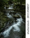 A clear mountain stream tumbling over moss-covered boulders in Kuragari Valley, Okazaki, Aichi, Japan. Silky rapids and fresh green foliage convey coolness and calm, perfect for travel, wellness, healing visuals and natural backgrounds.
