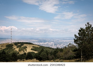 Clear mountain view of Tbilisi, Georgia, with rolling hills in the foreground and a partly cloudy sky above. The city stretches into the distance, framed by a scenic horizon - Powered by Shutterstock