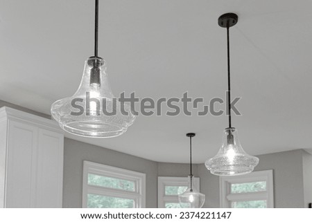 Clear Penant Lights Over Kitchen Island with Black Metal Rod in Blank Ceiling