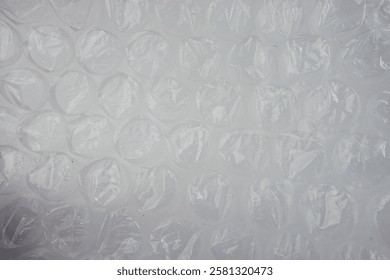 Clear plastic bubble wrap material, ideal for packaging, protection, or craft purposes. Transparent texture with soft lighting emphasizes the cushioning air-filled pockets in clean background setting