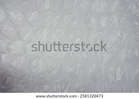 Clear plastic bubble wrap material, ideal for packaging, protection, or craft purposes. Transparent texture with soft lighting emphasizes the cushioning air-filled pockets in clean background setting