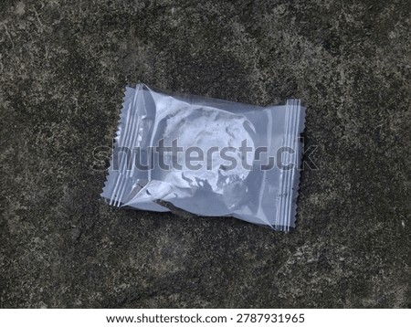 Clear plastic candy wrapper, empty snack packaging on ground, discarded litter on asphalt, small translucent refuse, photo object, design material, graphic resource, raw picture, editable image, cut out, removable background, unedited and natural look 